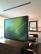 A large painting hangs from an Xpo Rail Track installed on the ceiling.