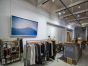 A large picture is displayed on the wall by two Loop-End stainless steel cables coiled on the beam in a clothes store.