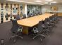 Une salle de conférence avec des chaises et une table. Un système d'accrochage tendu présente des photos suspendues devant le mur de séparation en verre. Les photos sont tendues entre des Pieds fixes longs et courts installés au sol et au plafond.