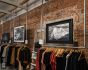 Three pictures are displayed on the brick wall by Loop-End stainless steel cables coiled on the wooden beam of a clothes store.