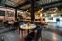 A cozy and chic restaurant with tables and chairs and panels suspended by sturdy hanging tracks.