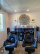 Un salon de coiffure avec des chaises noires divisées par un panneau de verre suspendu au plafond par des Pieds courts et fixé au sol par des Pieds longs.