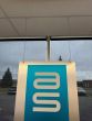 A metal sign hanging from the grid ceiling with Drop Ceiling Hangers for T Bar.