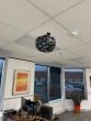 A Halloween decoration in the shape of a black pumpkin is suspended from the ceiling by Drop Ceiling Hangers for T Bars.