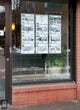 A real estate agency exhibits its listings into the front window with acrylic pockets suspended by a tensioned hanging system, fixed piers and stainless steel cables.