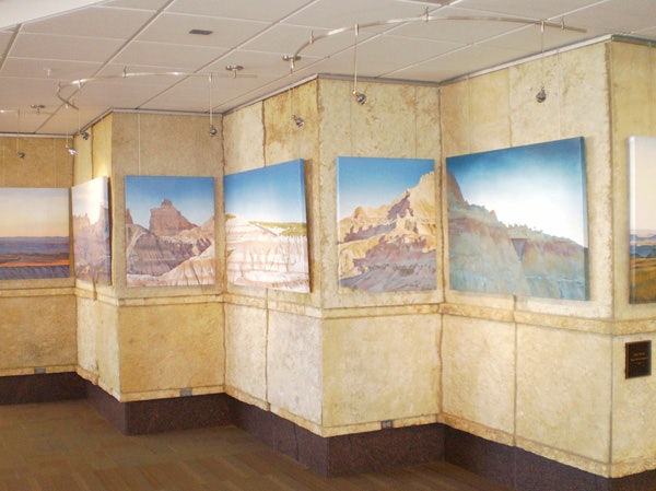 Stretched canvas prints suspended on stone walls at Rapid City Regional Airport (RAP) using Classic System by AS Hanging Systems. 