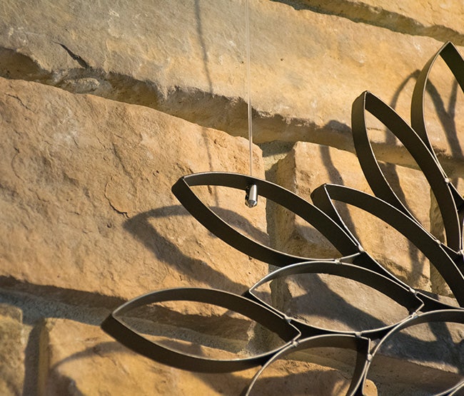 Metal art piece suspended by P-End Nylon Cord fitted with a Cable Stop.
