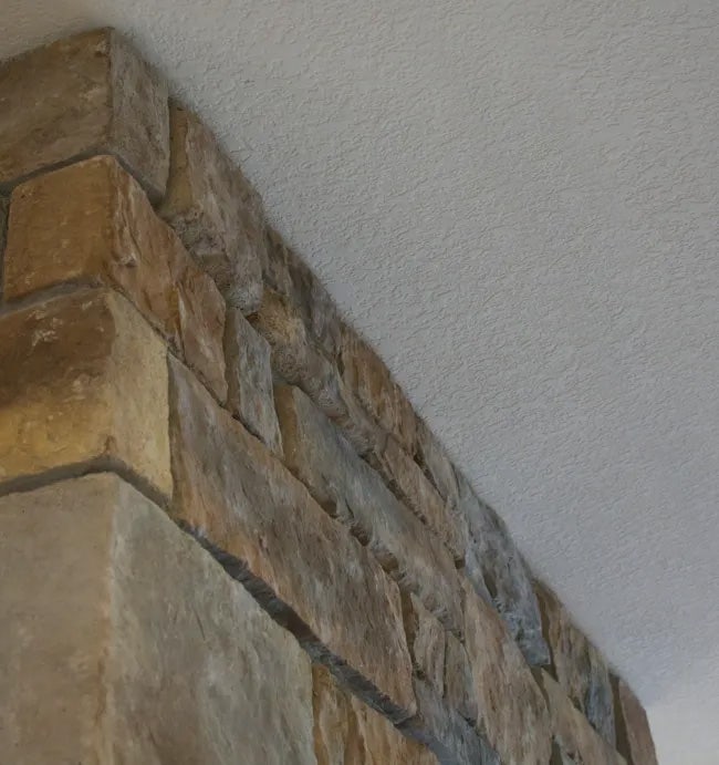 Stone fireplace with irregular front surface.